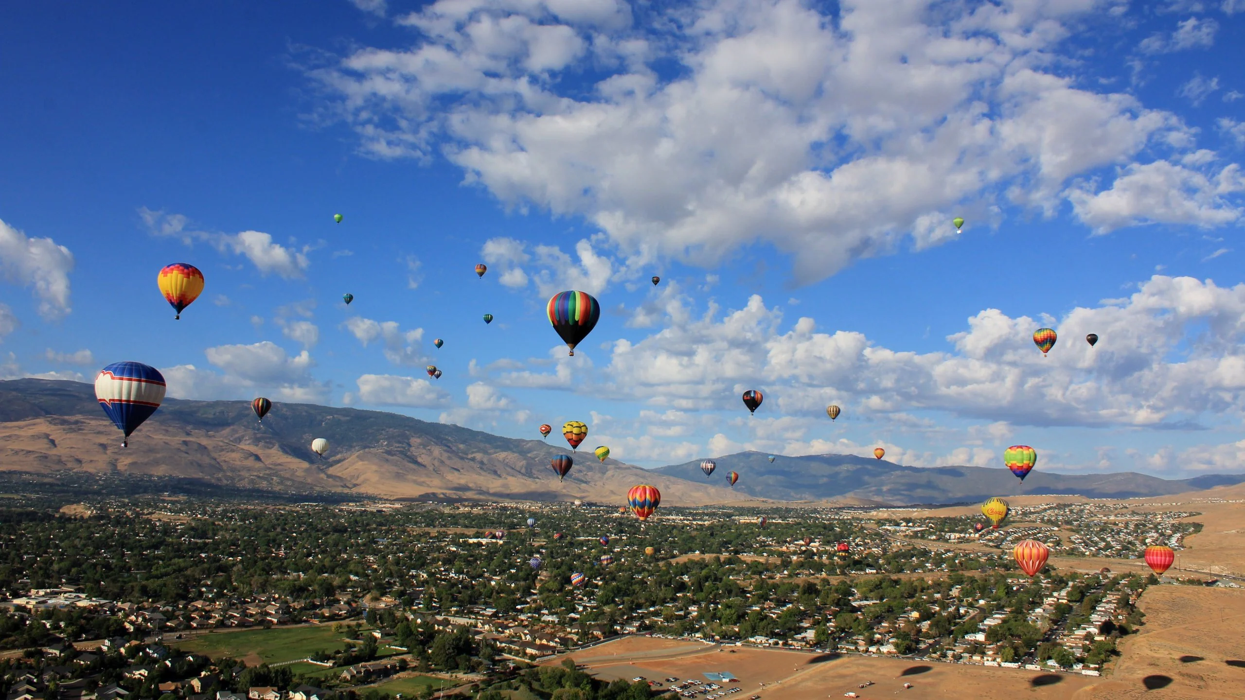 Colorful hot air balloons floating above Sparks, Nevada, on a clear day, illustrating the relaxing atmosphere served by local massage therapists.