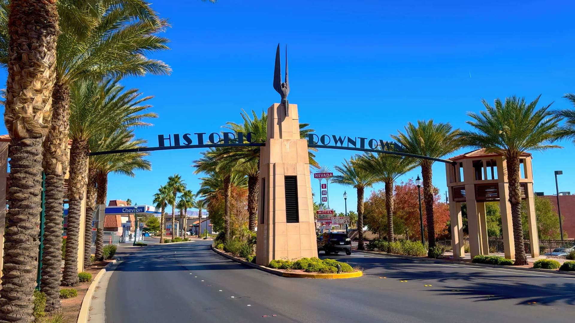 Downtown Boulder City entrance sign with palm trees under clear Nevada sky near Lake Mead and Hoover Dam