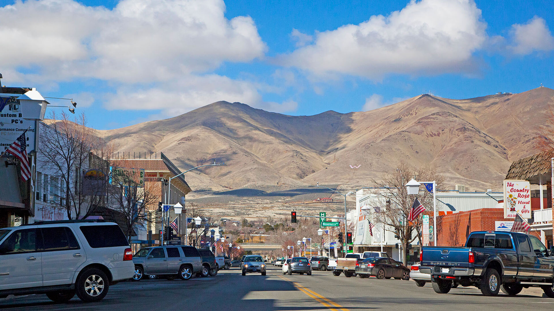 Downtown Winnemucca NV – Main Street view with mountain backdrop Downtown Winnemucca Nevada main street with cars, historic storefronts, and desert mountains in the background, highlighting a small-town high desert setting for massage and wellness services